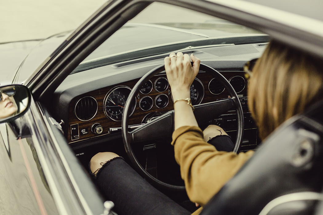 women with sunglasess driving her vintage vehicle