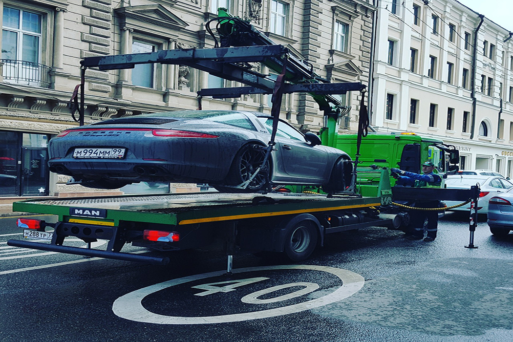 tow truck using a crane to tow a porsche 911